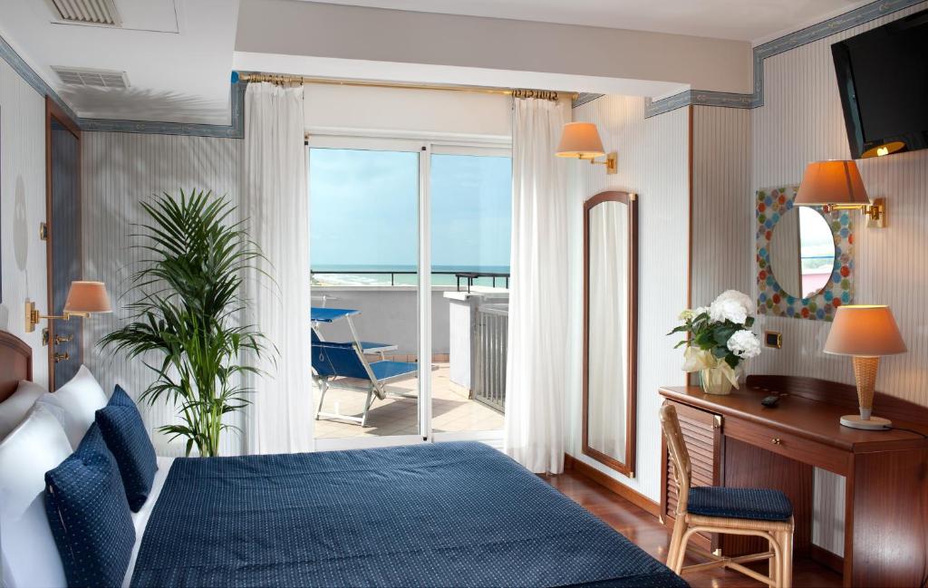 une chambre avec un lit et un bureau et un balcon dans l'établissement Atilius Hotel & Suites, à Riccione