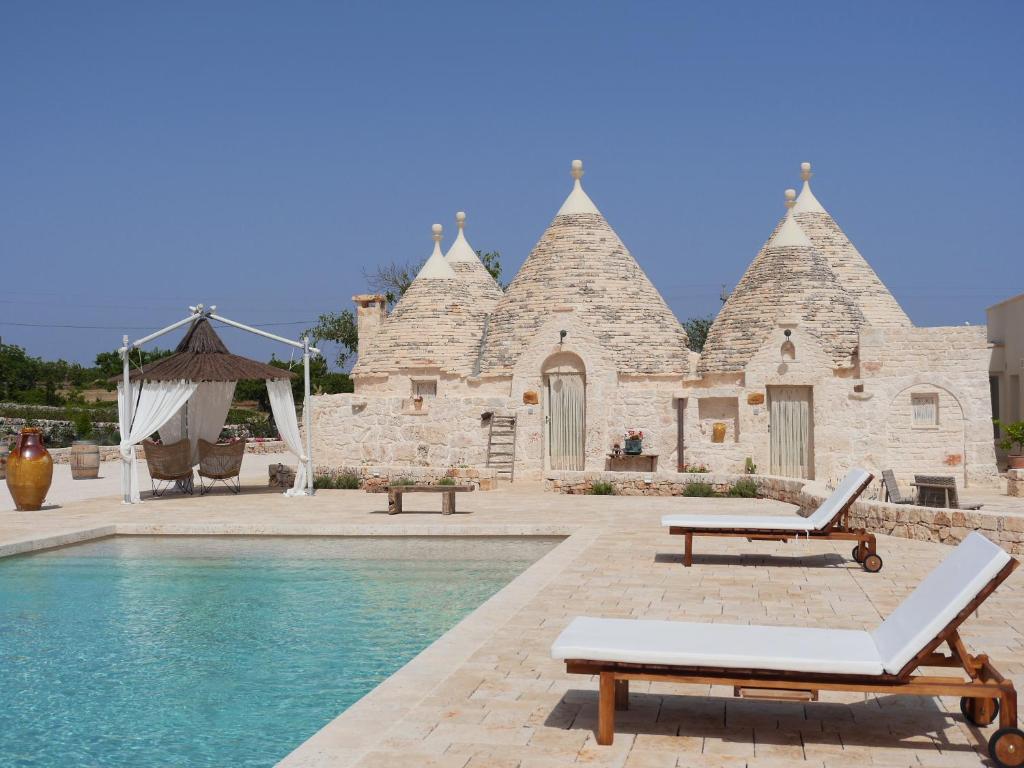 - un bâtiment en pierre avec une piscine en face dans l'établissement Trulli Terra Viva, à Alberobello