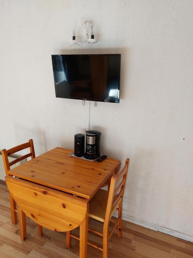 une table en bois avec deux chaises et une télévision murale dans l'établissement Appartement vacances à la montagne - Massif des Brasses, à Bogève