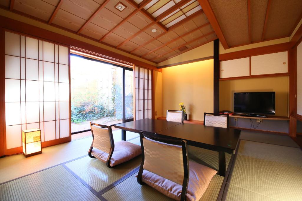 une chambre avec une table, deux chaises et une télévision dans l'établissement Hotel Tamanoyu, à Matsumoto