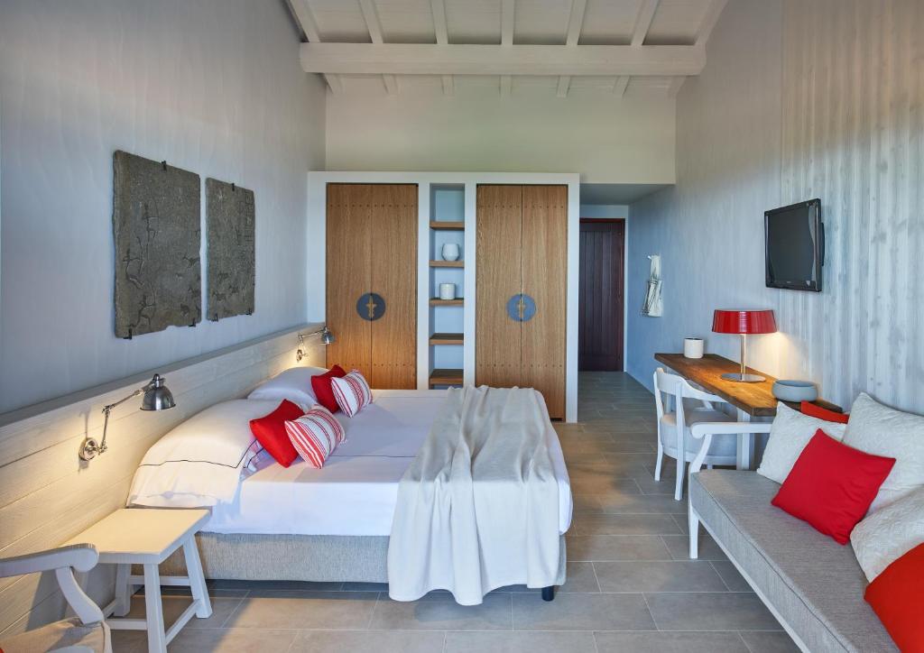 une chambre avec un grand lit et un canapé dans l'établissement Due Lune Puntaldia Resort & Golf, à San Teodoro
