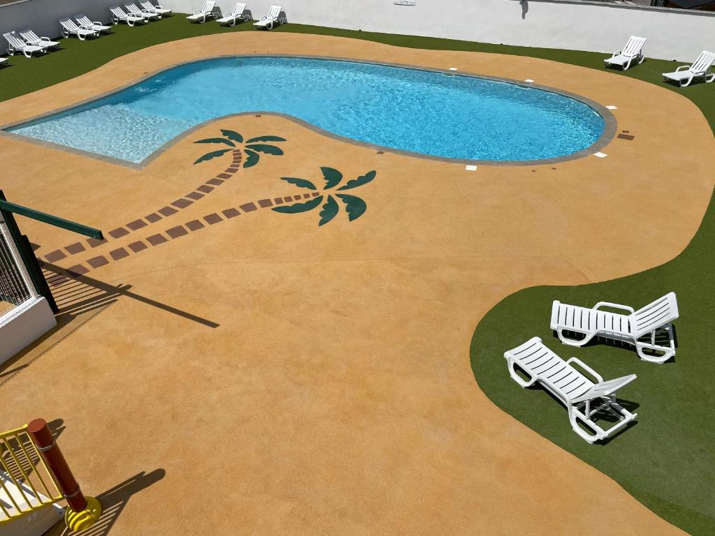une piscine avec deux chaises longues et une piscine dans l'établissement Camping LES PEUPLIERS, à Hyères