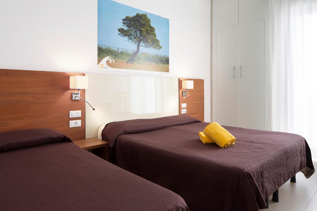 une chambre d'hôtel avec deux lits et un oreiller jaune dans l'établissement Hotel President, à Bibione