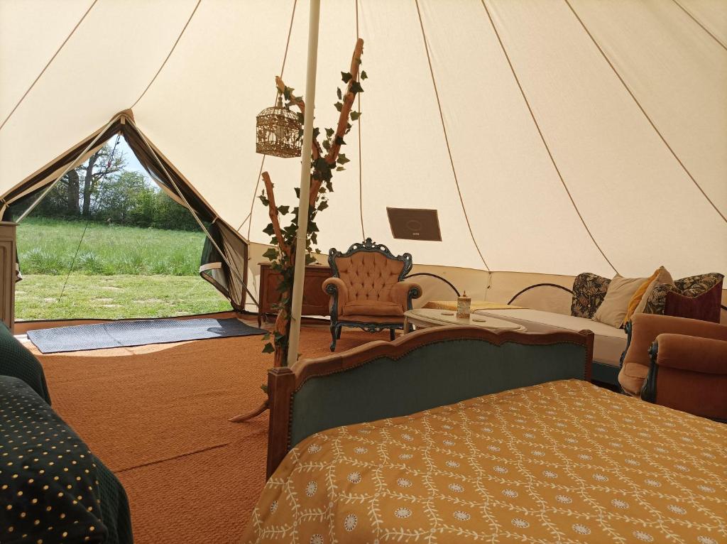 une chambre avec une tente avec un lit et une table dans l'établissement La Toile sous Les Étoiles, à Charron