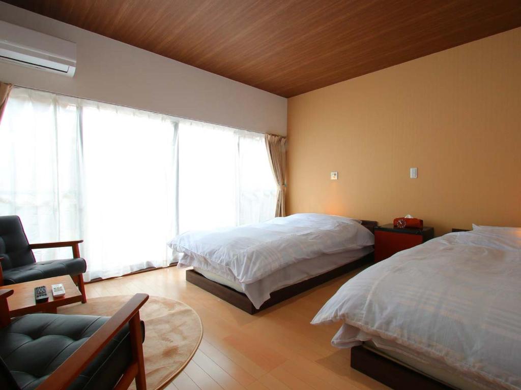 une chambre avec deux lits et une chaise et une fenêtre dans l'établissement Minshuku Shiroyama, à Taketa