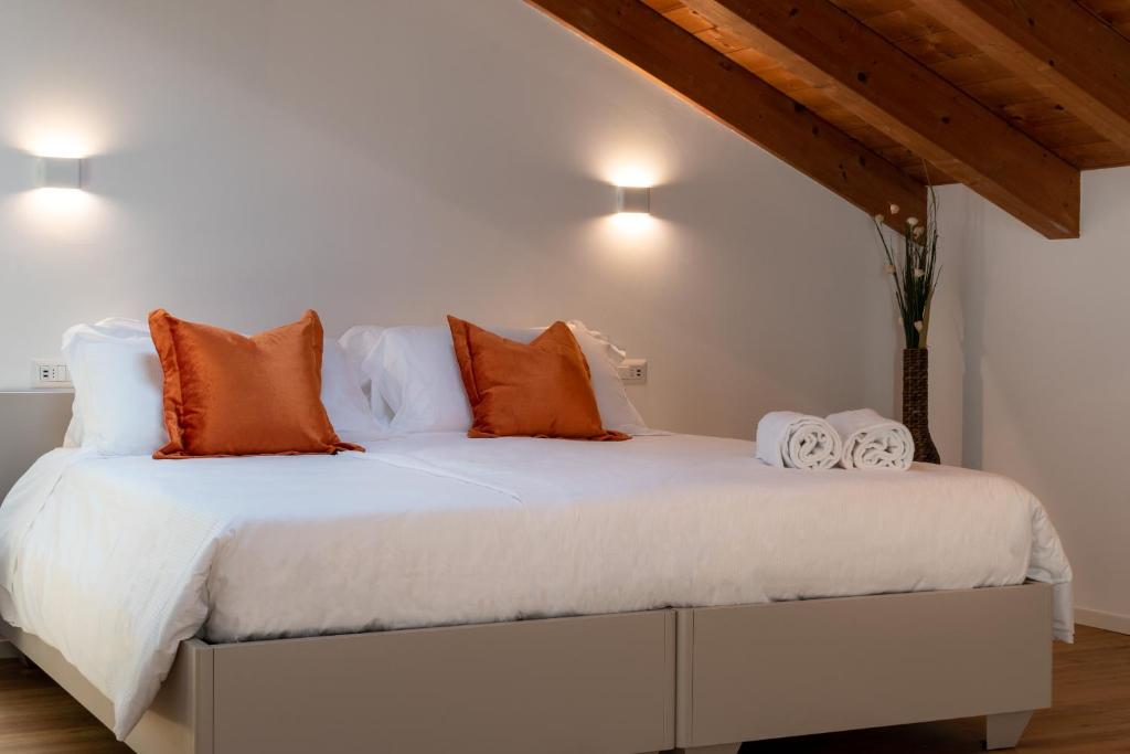 une chambre avec un lit blanc avec des oreillers orange dans l'établissement Superior Beach Aparthotel, à Lido di Jesolo