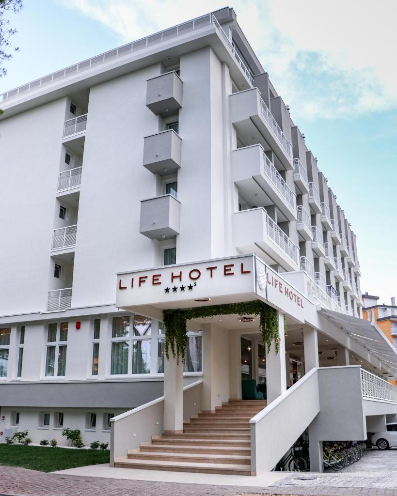 un bâtiment avec un panneau d'hôtel vivant sur celui-ci dans l'établissement Life Hotel 4 Superior, à Bibione
