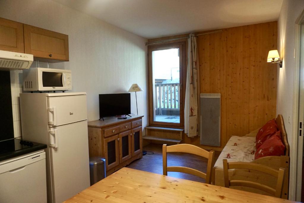 Il comprend une cuisine équipée d'un réfrigérateur et d'une table avec une table de cuisine. dans l'établissement T2 skis aux pieds Les Terrasses de la Bergerie, à Orcières
