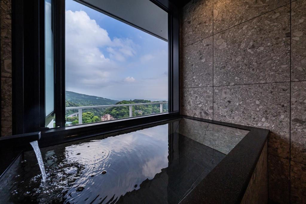 La salle de bains est pourvue d'une fenêtre et d'une baignoire avec vue. dans l'établissement Kirishima Kokusai Hotel, à Kirishima