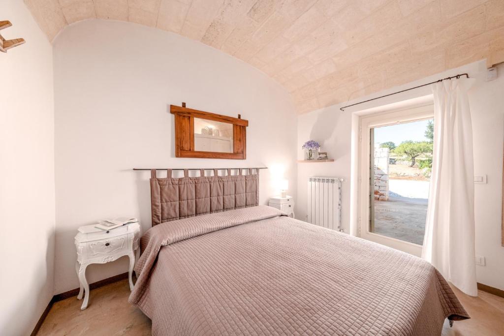 une chambre avec un grand lit et une fenêtre dans l'établissement HelloAPULIA Typical Cottage Lamia delle Murge - Private Pool & Scenic Hilltop Retreat - Pet friendly, à Ostuni