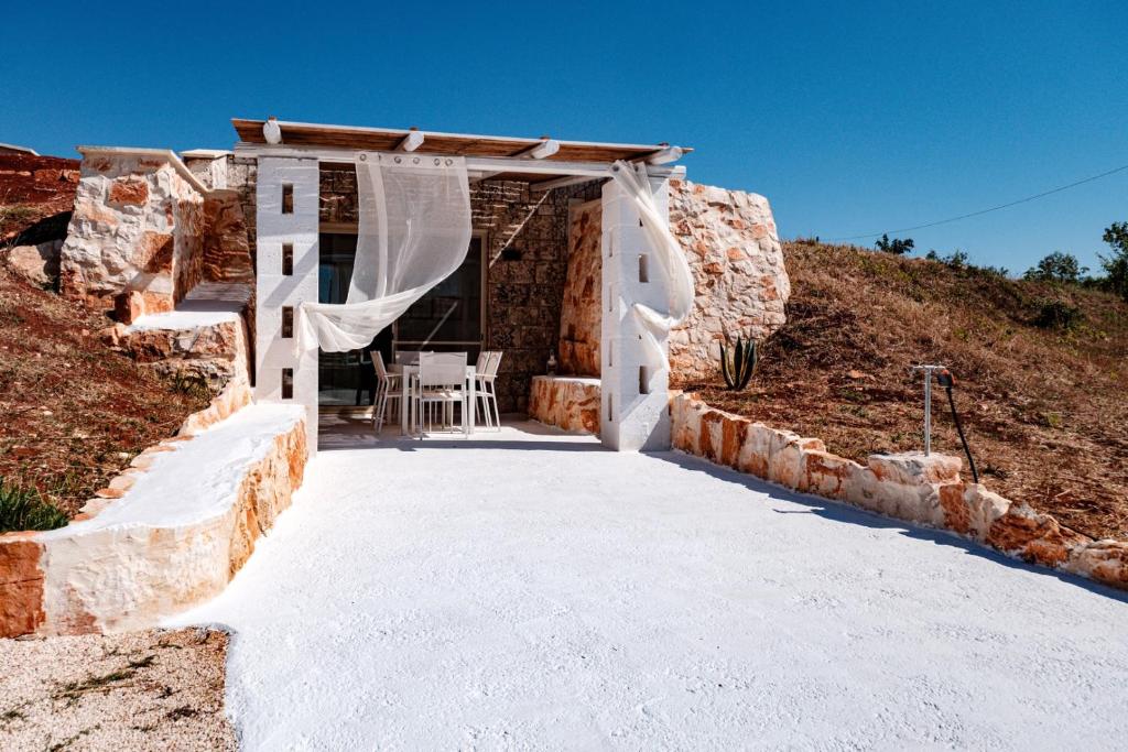 un bâtiment en pierre avec une table et un rideau blanc dans l'établissement HelloAPULIA Typical Cottage Lamia delle Murge - Private Pool & Scenic Hilltop Retreat - Pet friendly, à Ostuni