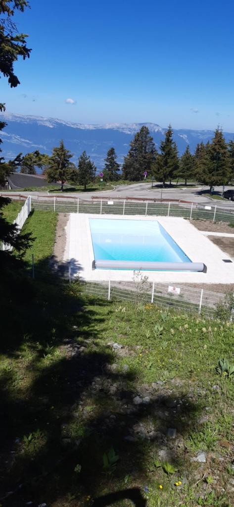 - une grande piscine dans un champ avec une pelouse dans l'établissement Studio aux pieds des pistes Roche Béranger, à Chamrousse