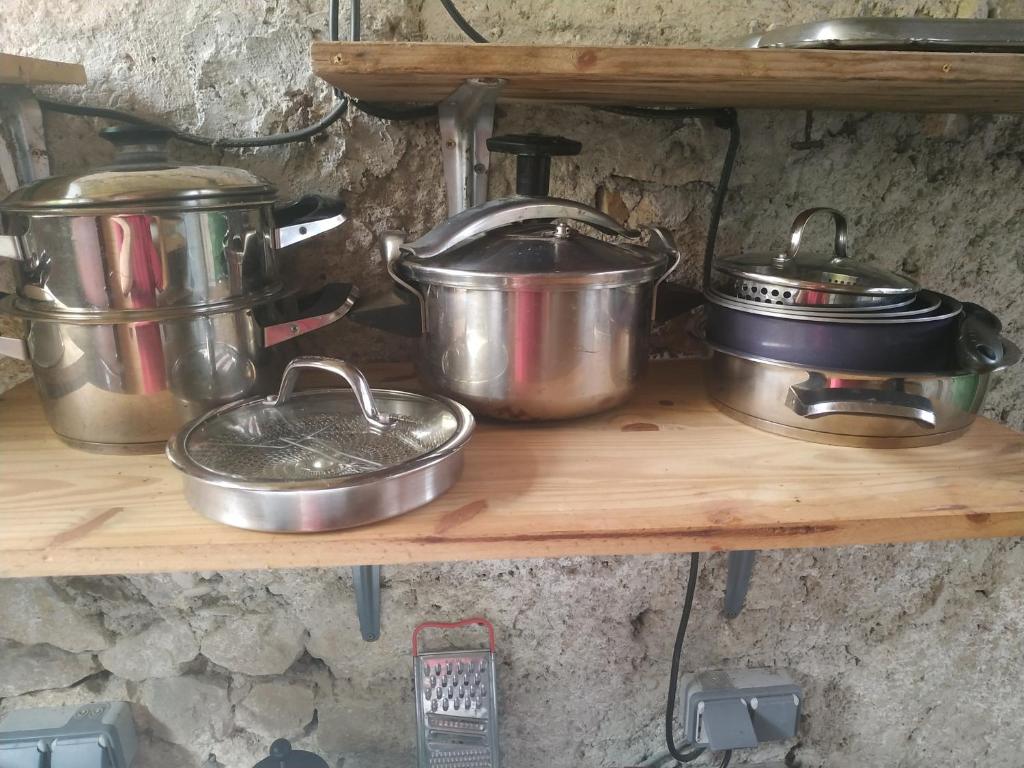 Une bande de casseroles et de poêles sur une étagère dans l'établissement Eco Yourte Lac du Bourget, à Conjux