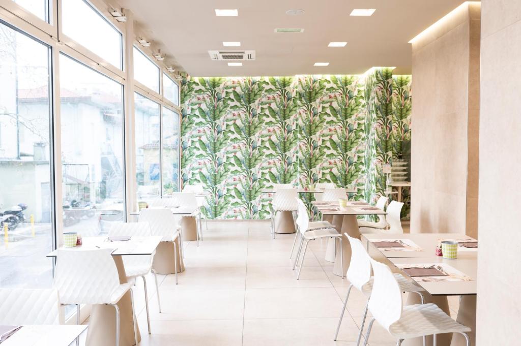un restaurant avec des tables blanches, des chaises blanches et une fresque murale. dans l'établissement L'Hotel, à Rimini