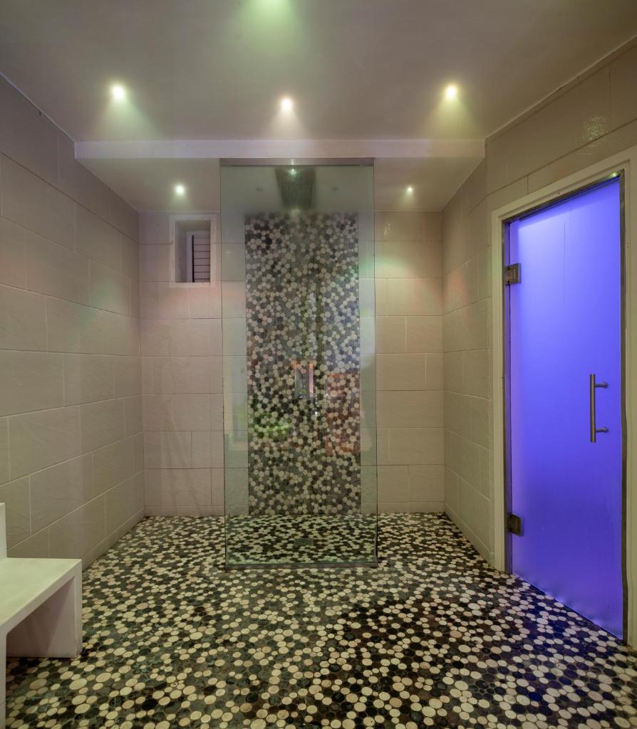 La salle de bains est pourvue d'une douche avec une porte violette. dans l'établissement L'Hotel, à Rimini