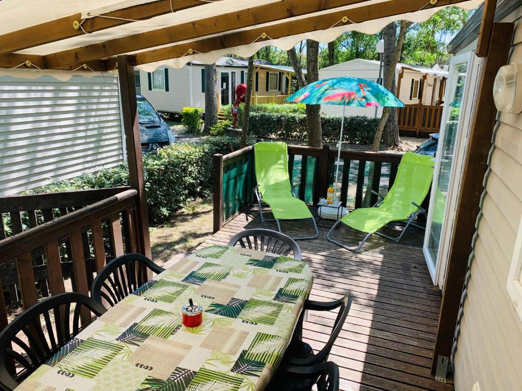une terrasse avec une table, des chaises et un parasol dans l'établissement Mobil home « lysea », 6p, Clim, à Agde 5 autres photos