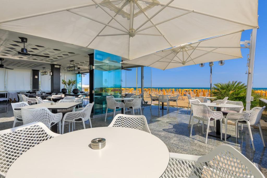 un restaurant avec des chaises blanches, des tables et des parasols dans l'établissement Hotel Gritti, à Lido di Jesolo 46 autres photos