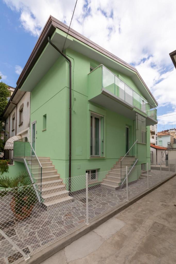 une maison verte avec des escaliers devant dans l'établissement Residence Diffuso Arcobaleno, à Gabicce Mare