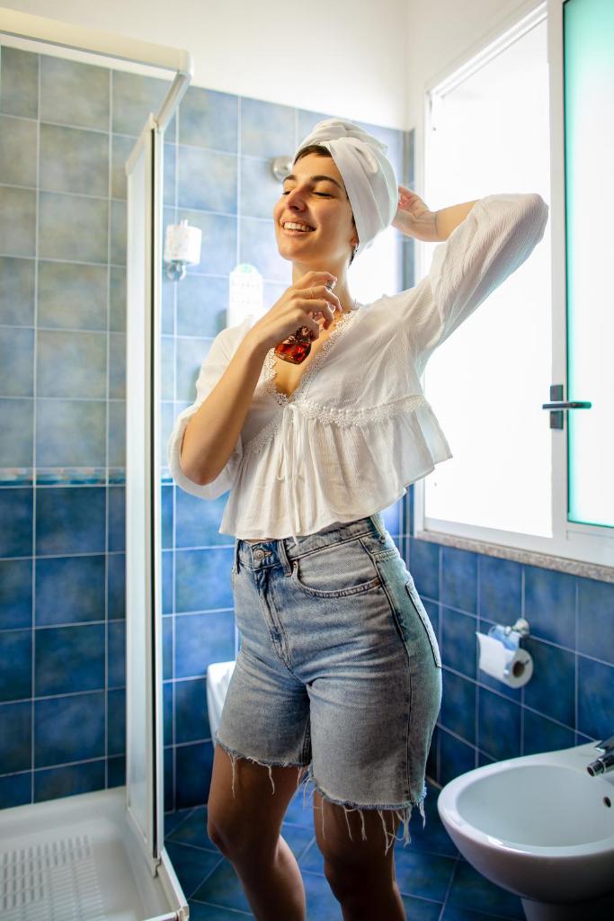 une femme est debout dans la douche dans une salle de bains dans l'établissement New Bristol Sport Hotel, à Cesenatico