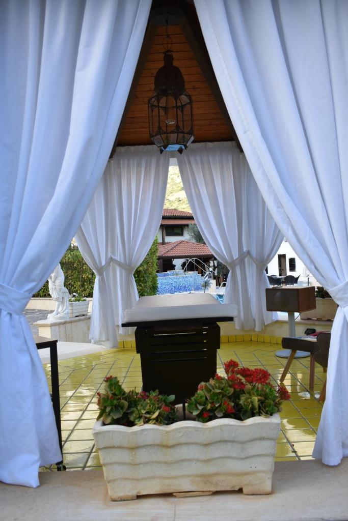 - un kiosque orné de rideaux blancs et de fleurs dans l'établissement Villa Caterina, à Torretta