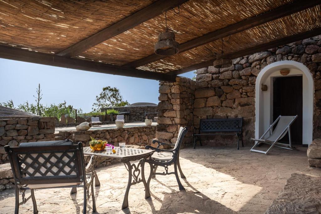 un patio avec une table et des chaises et un mur en pierre dans l'établissement Tenuta Dammuso Soledad, à Scauri