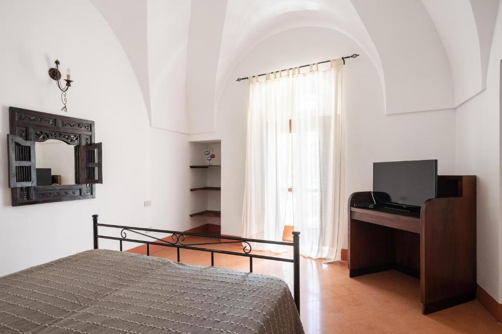 une chambre avec un lit, un bureau et une fenêtre dans l'établissement Tenuta Dammuso Soledad, à Scauri