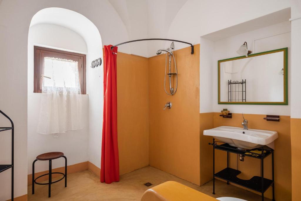 La salle de bains est pourvue d'un lavabo et d'un rideau de douche rouge. dans l'établissement Tenuta Dammuso Soledad, à Scauri
