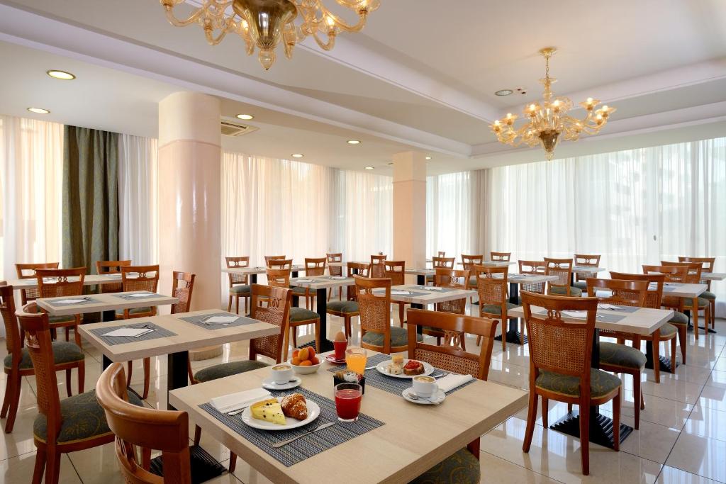 un restaurant avec des tables, des chaises et un lustre dans l'établissement Hotel Elisir, à Rimini 23 autres photos