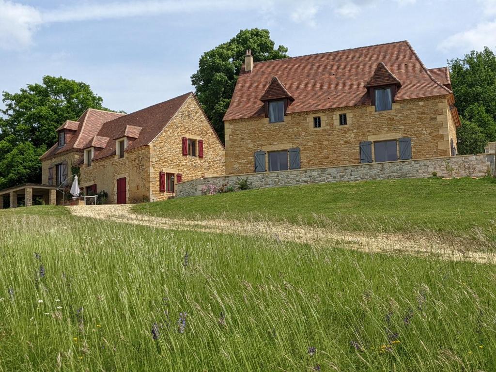 une grande maison en pierre sur une colline avec une pelouse dans l'établissement Gite de Fleurie - Tursac, à Tursac
