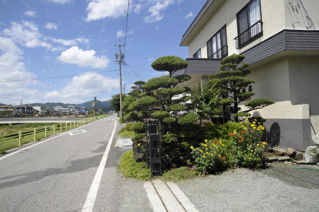 une maison avec un arbre sur le côté d'une route dans l'établissement Ryokan Seifuso, à Matsumoto