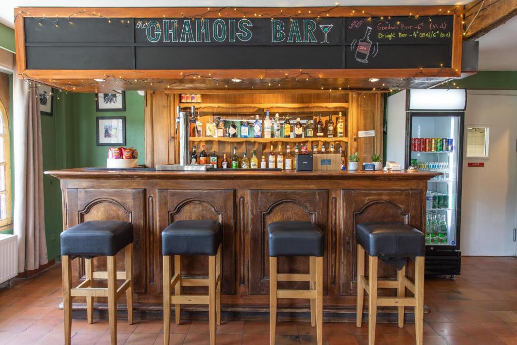 un bar avec quatre tabourets dans l'établissement Hotel le Chamois, à L'Alpe-d'Huez