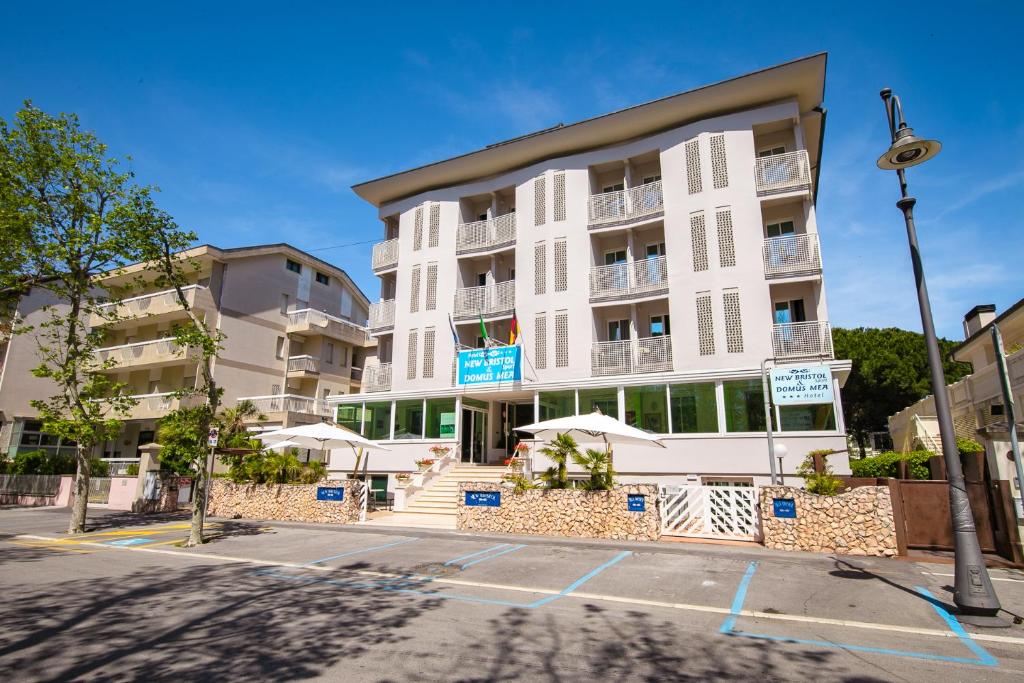 - un bâtiment blanc avec des parasols en face dans l'établissement New Bristol Sport Hotel, à Cesenatico