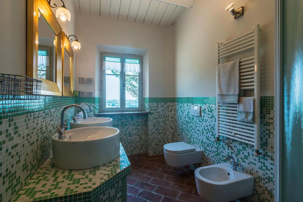 une salle de bain avec deux lavabos et une baignoire et des toilettes dans l'établissement Villa La Capuccina, à Corinaldo