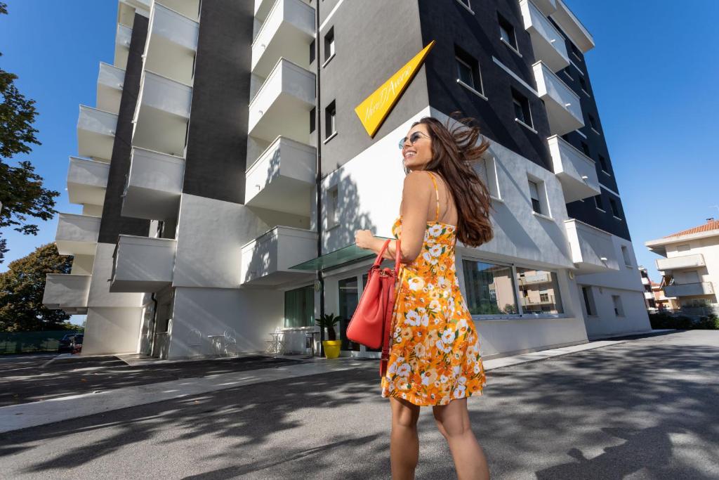 une femme en robe debout devant un bâtiment dans l'établissement Nero D'Avorio Apartments, à Rimini
