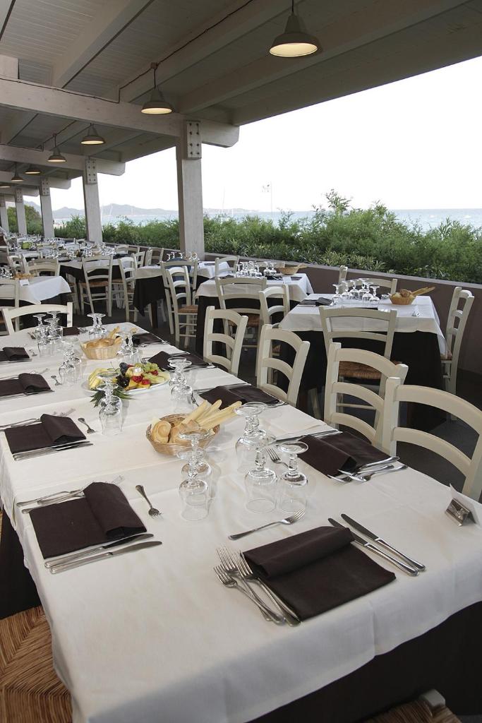 un groupe de tables et de chaises avec des nappes blanches dans l'établissement TH Costa Rei - Free Beach Resort, à Monte Nai