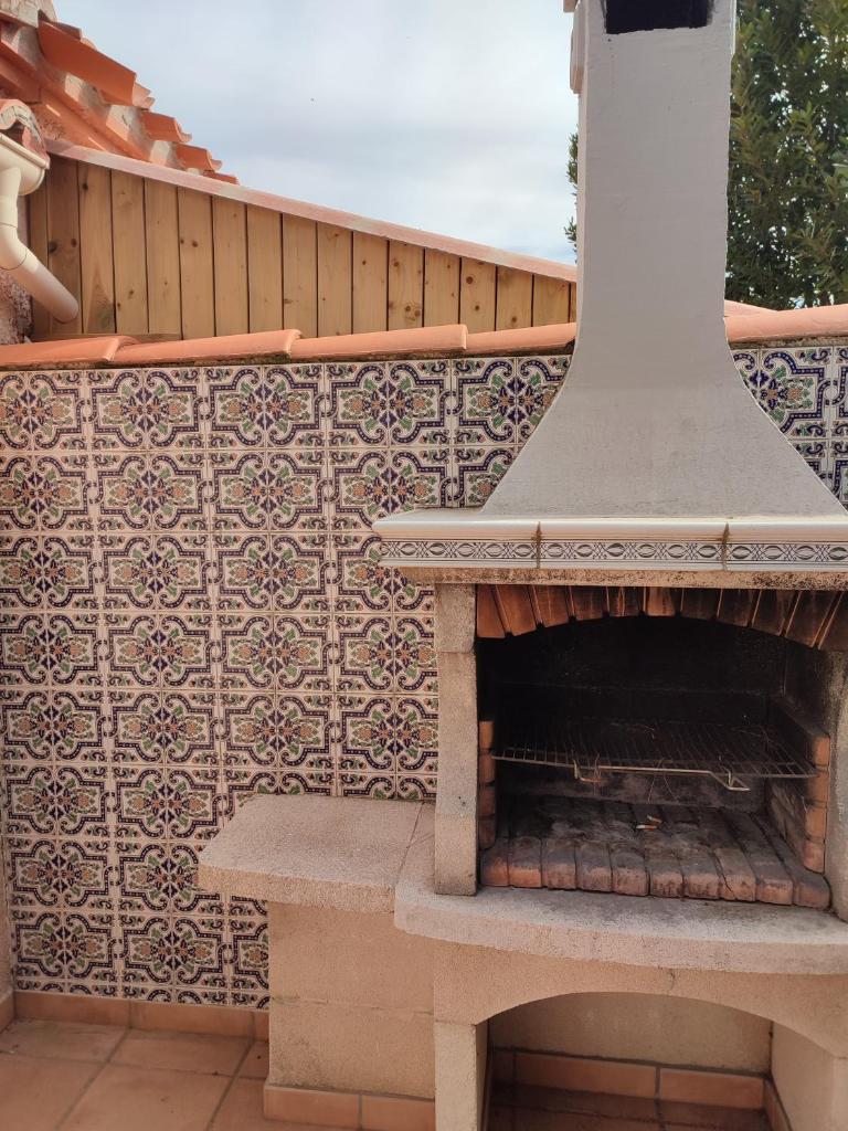 une cheminée extérieure avec un banc en face d'une clôture dans l'établissement Villa Casaleno gite La Cigale avec wi-fi, à Millas