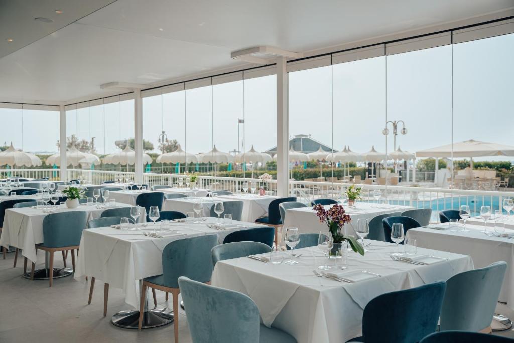 une pièce avec des tables et des chaises recouvertes de nappes blanches dans l'établissement Hotel Galassia Suites & Spa, à Lido di Jesolo