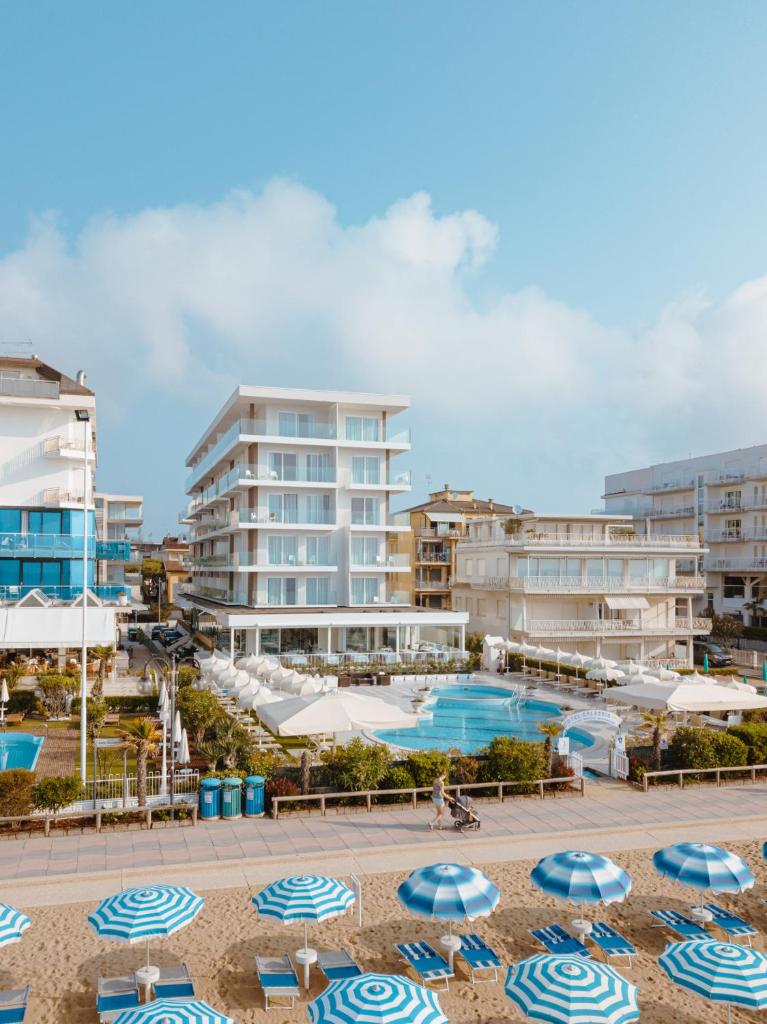 une plage avec des parasols et une piscine avec des bâtiments dans l'établissement Hotel Galassia Suites & Spa, à Lido di Jesolo