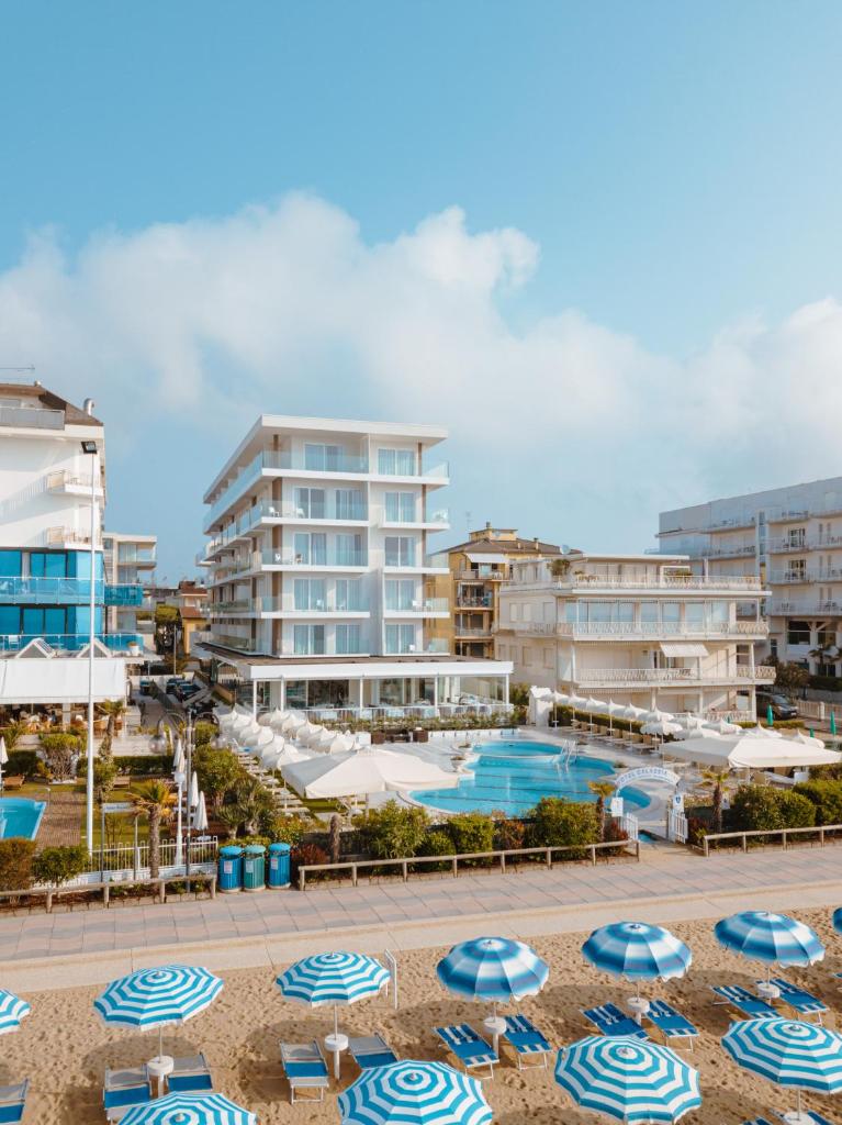 un complexe avec une piscine, des parasols et des bâtiments dans l'établissement Hotel Galassia Suites & Spa, à Lido di Jesolo