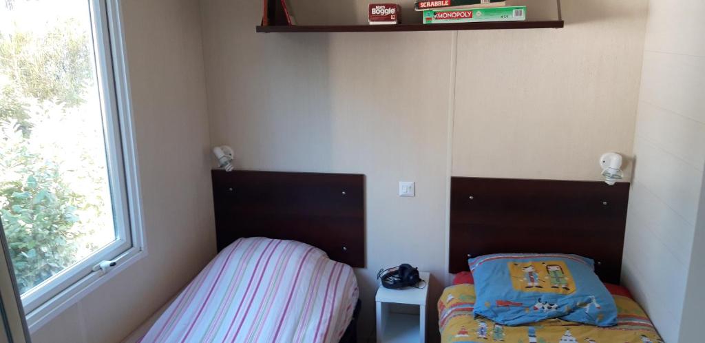 une petite chambre avec deux lits et une fenêtre dans l'établissement Mobil Home Lacanau Océan, à Lacanau