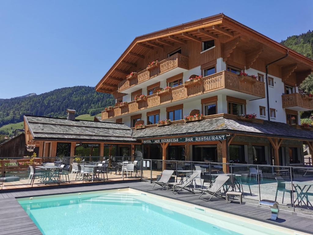 un hôtel avec une piscine devant un immeuble dans l'établissement Hôtel-Chalet Les Ecureuils Restaurant, Piscine, Jardin Garage, au Grand-Bornand