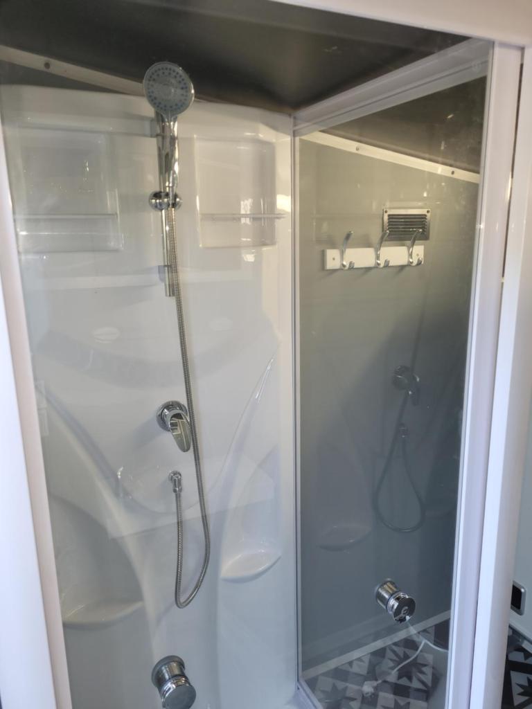 une douche avec une porte vitrée dans une salle de bain dans l'établissement Clos Des Monts, à Saint-Martin-des-Besaces