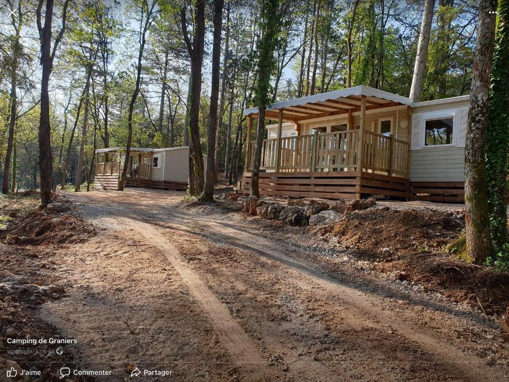 une cabane en rondins dans les bois avec un chemin de terre dans l'établissement Camping de Graniers, à Monoblet