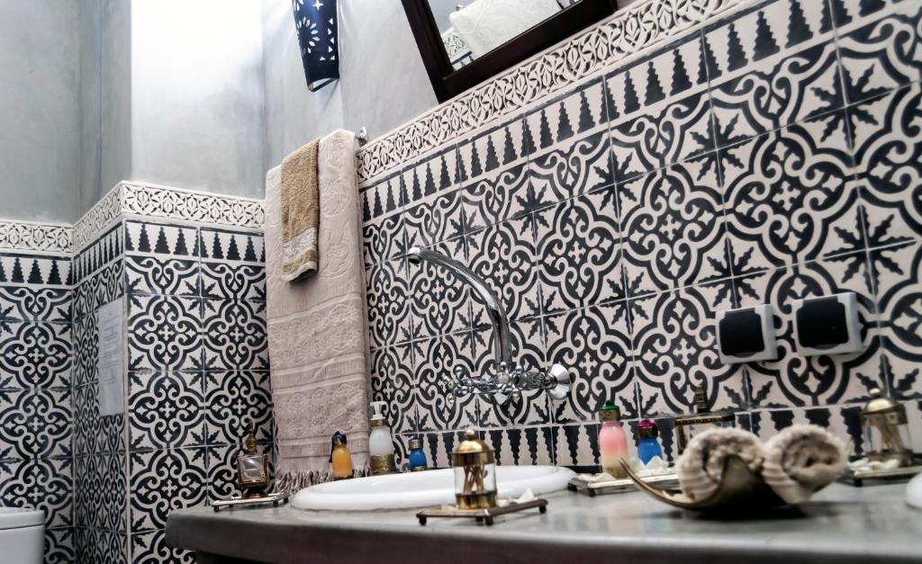 La salle de bains est pourvue d'un lavabo et de carrelage noir et blanc. dans l'établissement Riad Dar Mamouni, à Marrakech