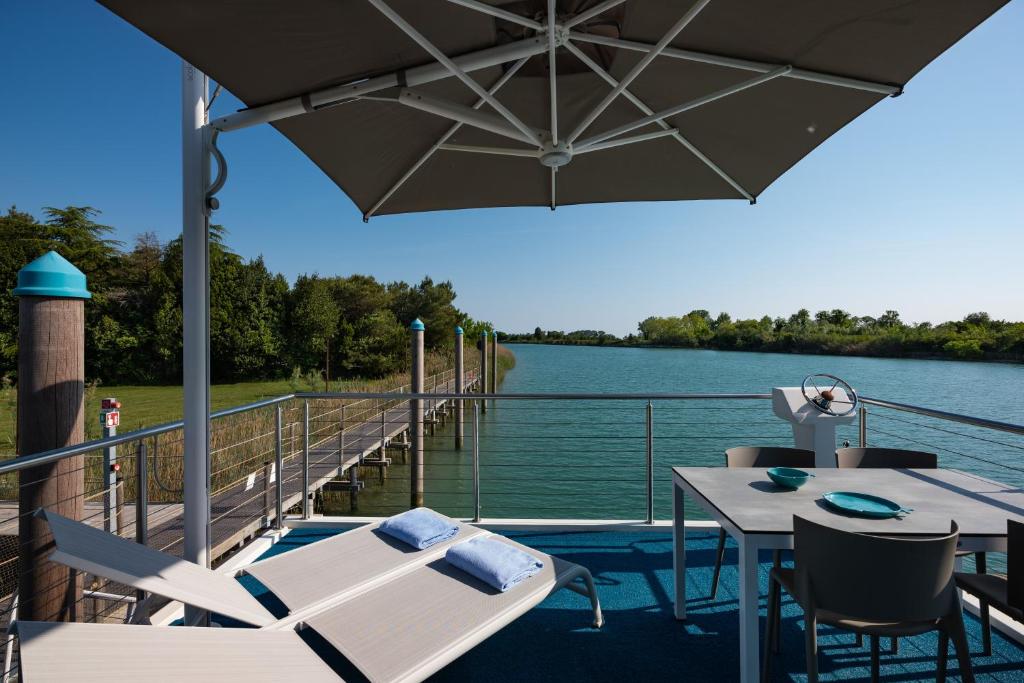 une terrasse avec une table, des chaises et un parasol dans l'établissement Marina Azzurra Resort, à Lignano Sabbiadoro