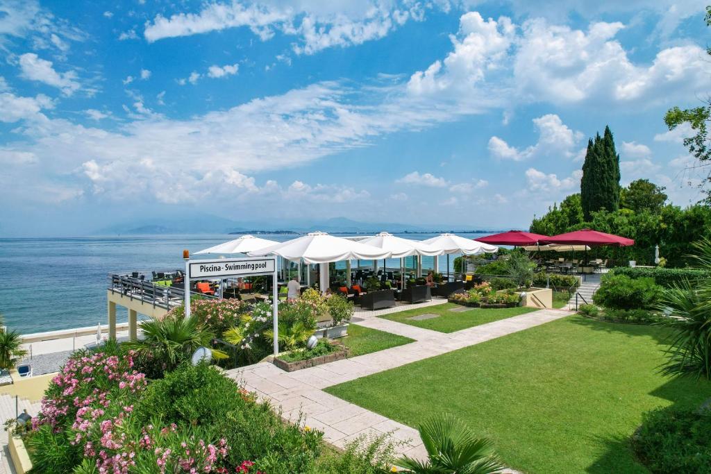 un jardin avec des parasols et l'océan en arrière-plan dans l'établissement Lido International, à Desenzano del Garda