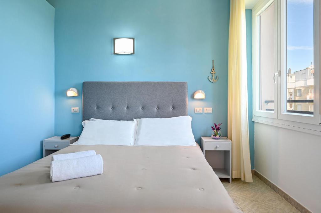 - une chambre bleue avec un grand lit et une fenêtre dans l'établissement Amadei Hotel Promenade, à Pesaro