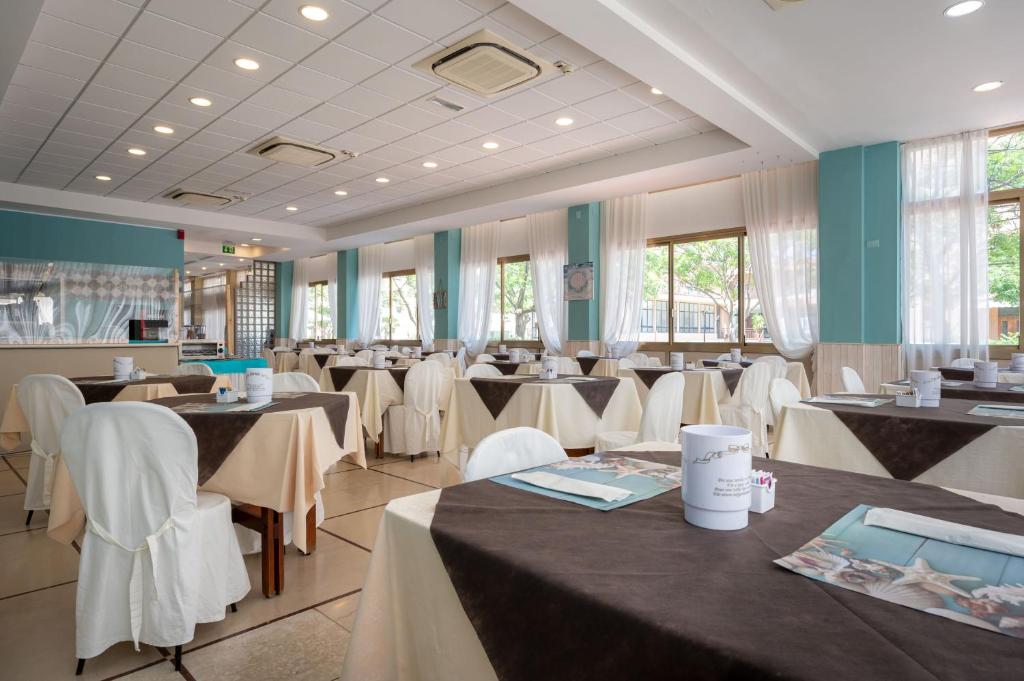 une salle à manger avec des tables et des chaises blanches dans l'établissement Amadei Hotel Promenade, à Pesaro