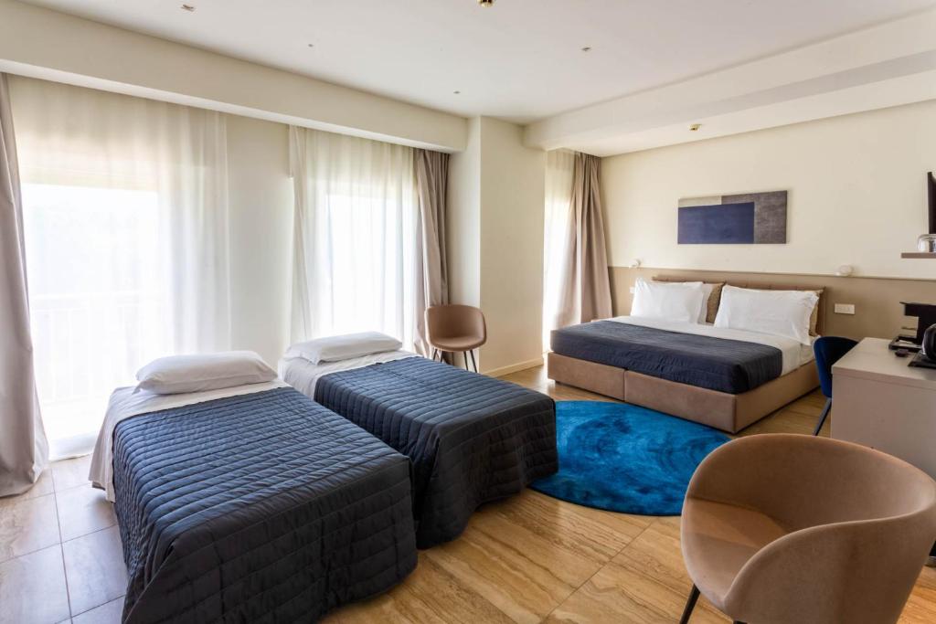 une chambre d'hôtel avec deux lits et une chaise dans l'établissement Hotel Petit Palais, sur le Lido de Venise