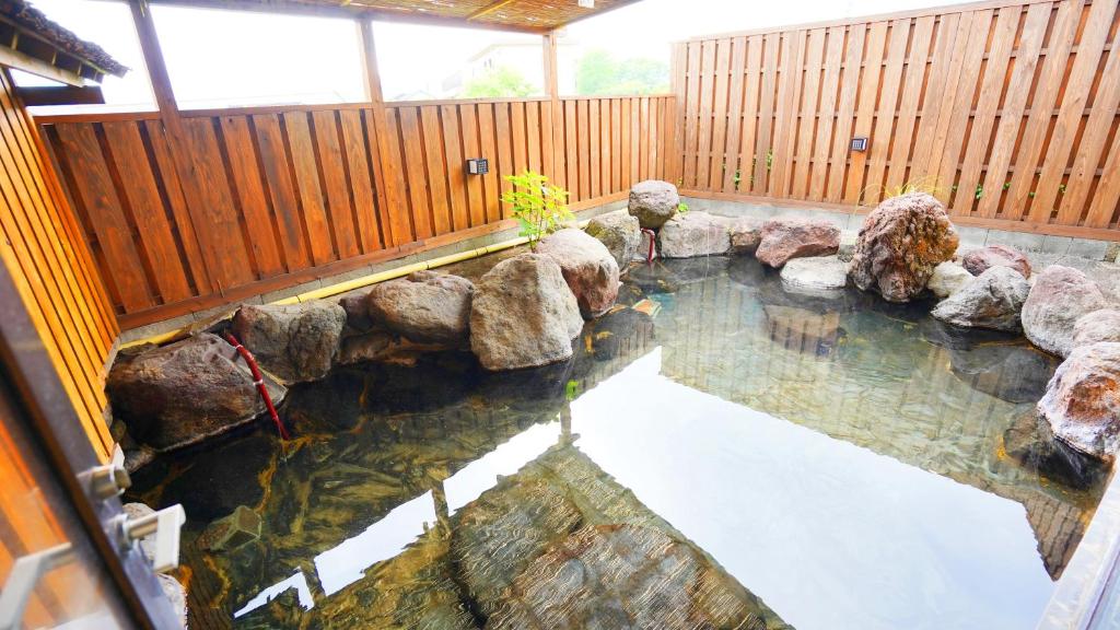 une piscine d'eau avec des rochers dans une arrière-cour dans l'établissement 素泊り旅館 Yururi, à Yufu